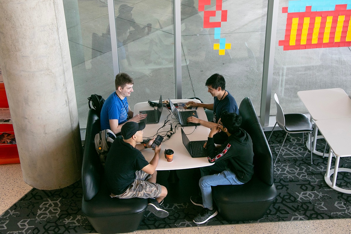Four people sitting at a table working on laptops - opens in a new tab