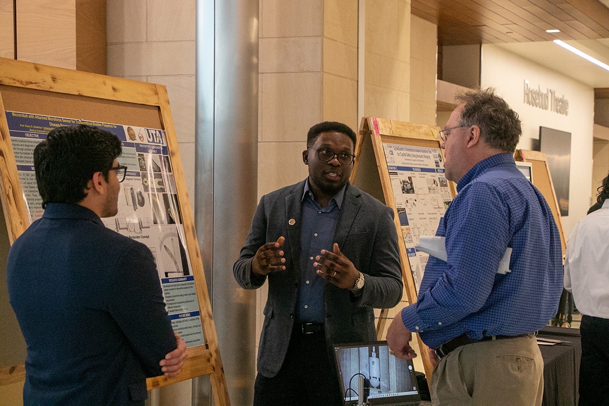 Man explaining his project to two other people at a UTA event - opens in a new tab