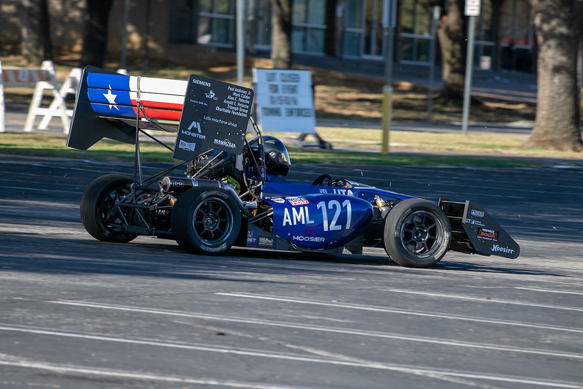 Person driving a UTA racecar through a parking lot - opens in a new tab